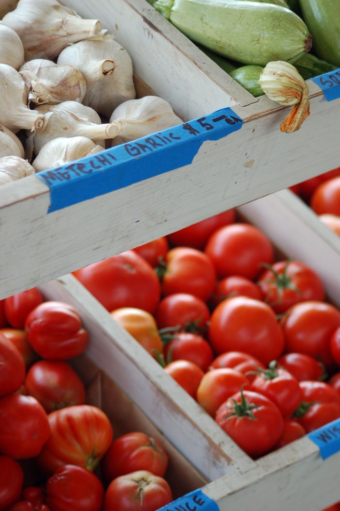 gallery-4 Close-up of fresh garlic, tomatoes, and zucchinis at a local farmers market.