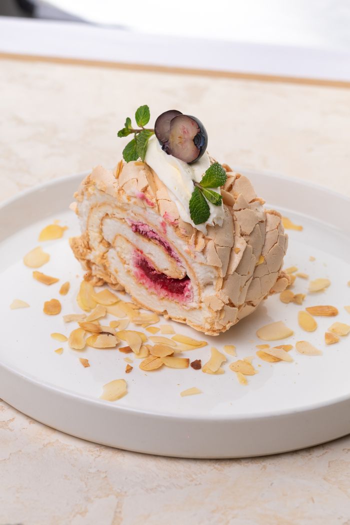 services-02 Mouth-watering meringue roulade topped with berries and cream, set on a white plate.