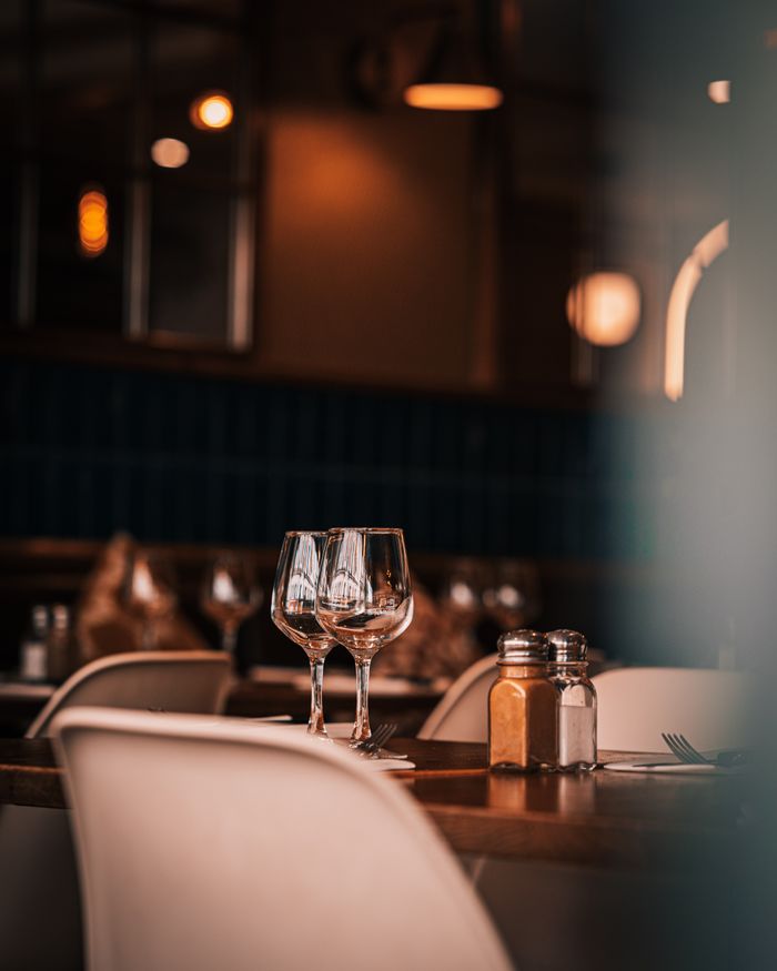 ours-journey Warmly lit Parisian restaurant showcasing elegant table setting with wine glasses.