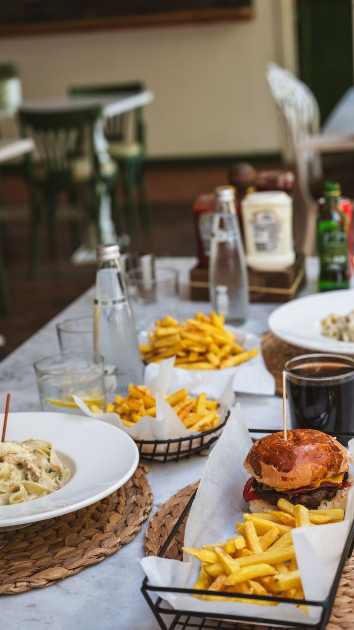 gallery-2 A table set for an outdoor meal featuring burgers, pasta, and fries, creating a casual dining ambiance.