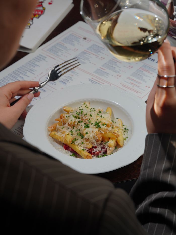 services-03 A detailed close-up of a gourmet pasta dish paired with white wine, set beside a dining menu.