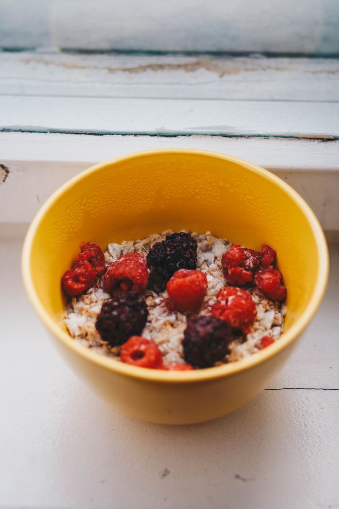 services-04 From above of bowl with delicious ripe strawberries and blackberries with cereals for breakfast placed on wooden table